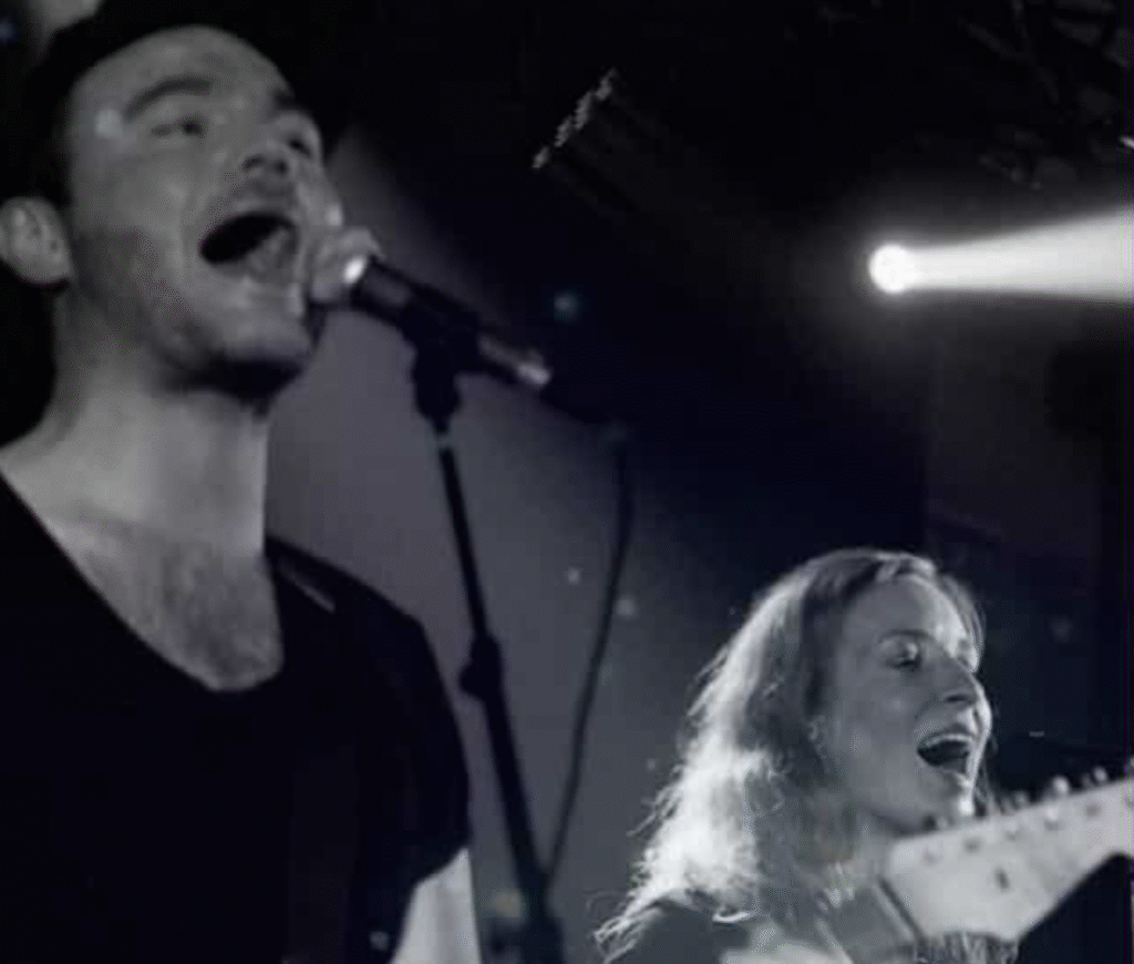 To musikere synger på en scene med guitarer