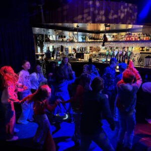 Børn danser under farvede lys på klubscene