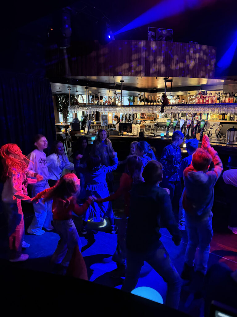 Børn danser under farvede lys på klubscene