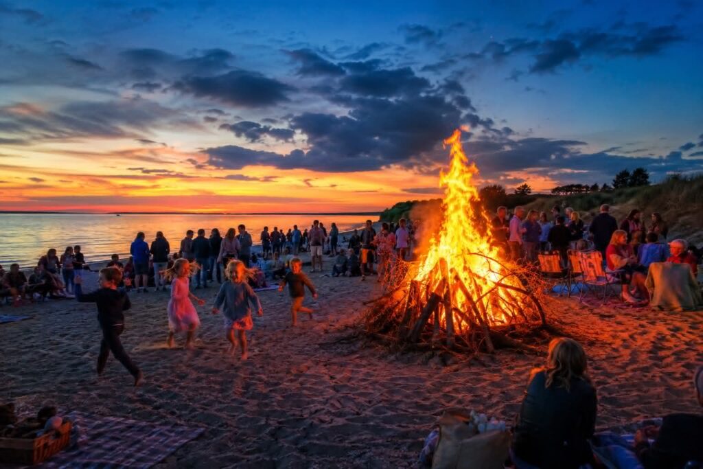 Bål på stranden ved solnedgang med mennesker